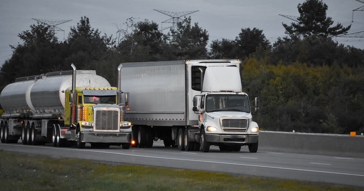 two semi trucks driving on road