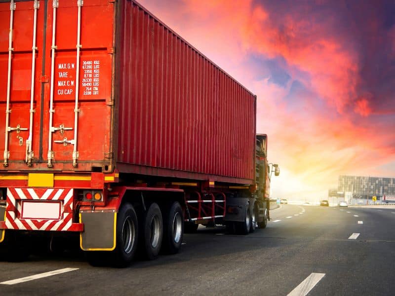 semi truck driving on highway at sunset